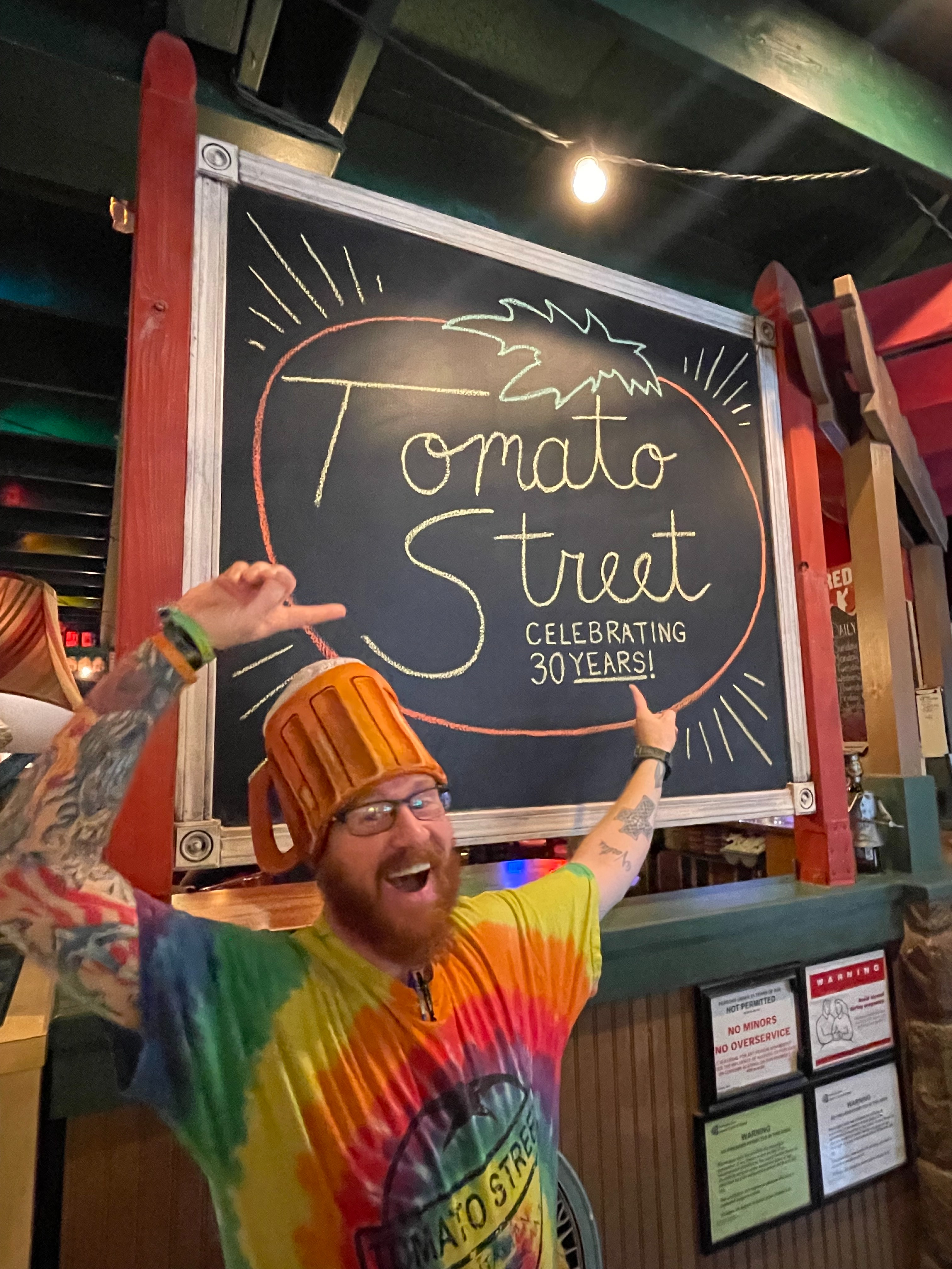 Tomato Street Employee pointing to 30 year anniversary sign