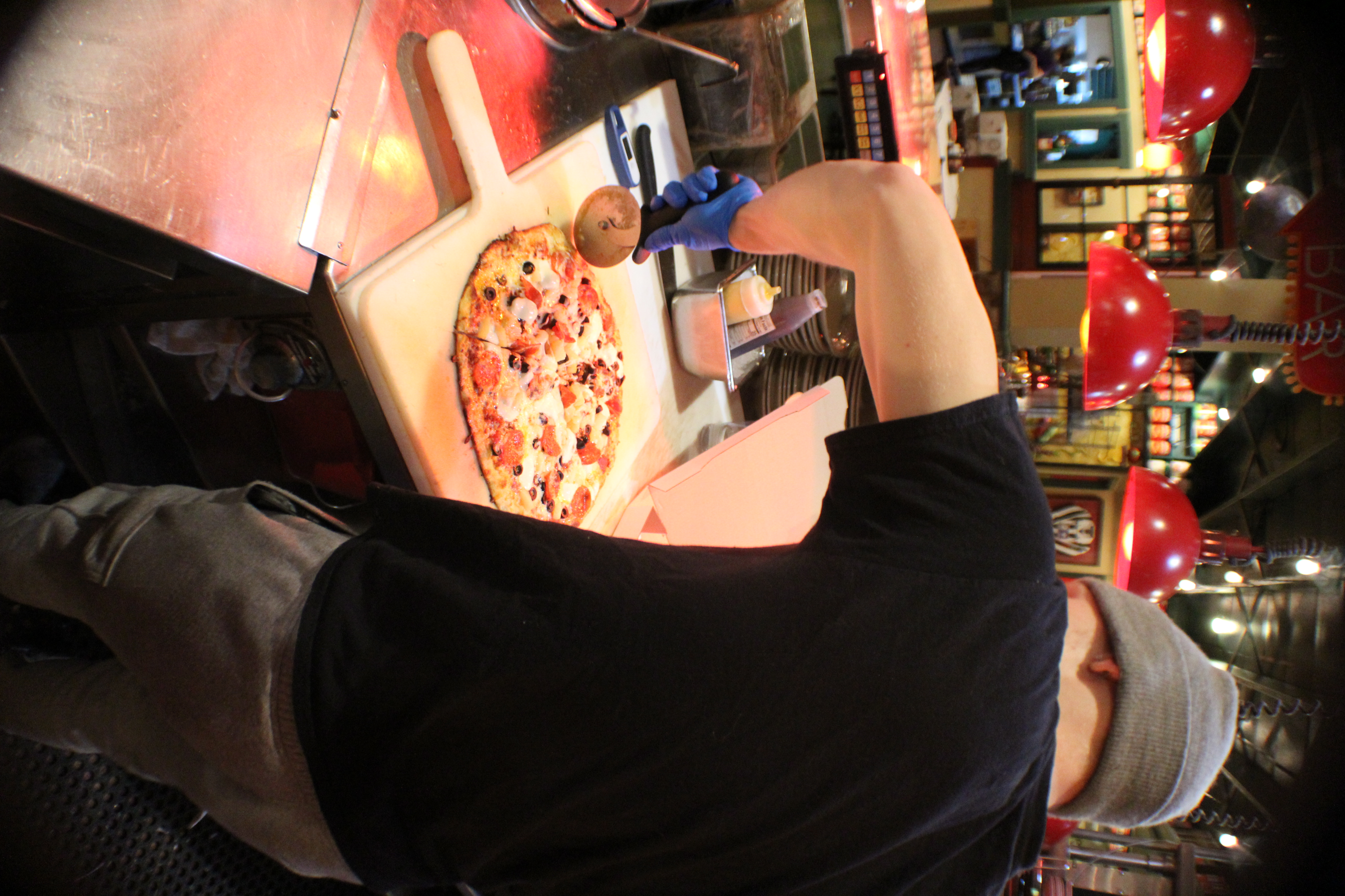 Pizza cook cutting a pizza in the Spokane Tomato Street kitchen
